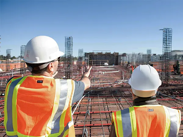 Trabajadores en obra viendo construcción con cascos blancos